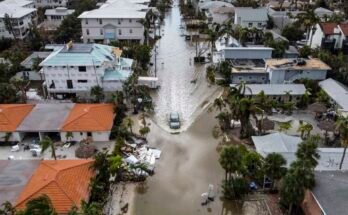Una foto en ángulo alto de un vehículo que conduce a una calle inundada después de que el huracán Milton, Siesta Key, Florida, el 10 de octubre de 2024, después de que el sistema meteorológico de los monstruos envió tornados que se volvieron a través del estado e inundaron las bandas de la región de la Bahía de Tampa.