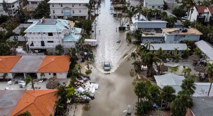 Una foto en ángulo alto de un vehículo que conduce a una calle inundada después de que el huracán Milton, Siesta Key, Florida, el 10 de octubre de 2024, después de que el sistema meteorológico de los monstruos envió tornados que se volvieron a través del estado e inundaron las bandas de la región de la Bahía de Tampa.