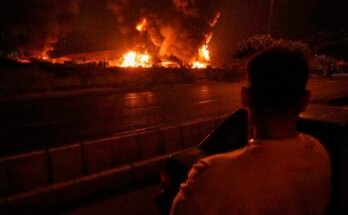 Un hombre mira las llamas que se elevan de una instalación de almacenamiento de petróleo después de que parecía haber sido golpeada por una huelga israelí en Teherán, Irán, el domingo 15 de junio de 2025.
