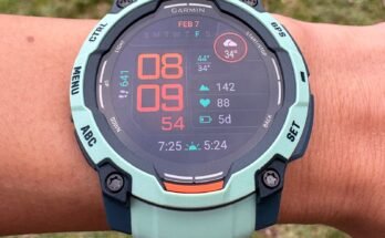 Vista aérea de una muñeca con un Garmin Instinct 3 Un rastreador de ejercicios en un reloj de brazalete con diseño turquesa y una gran pantalla digital