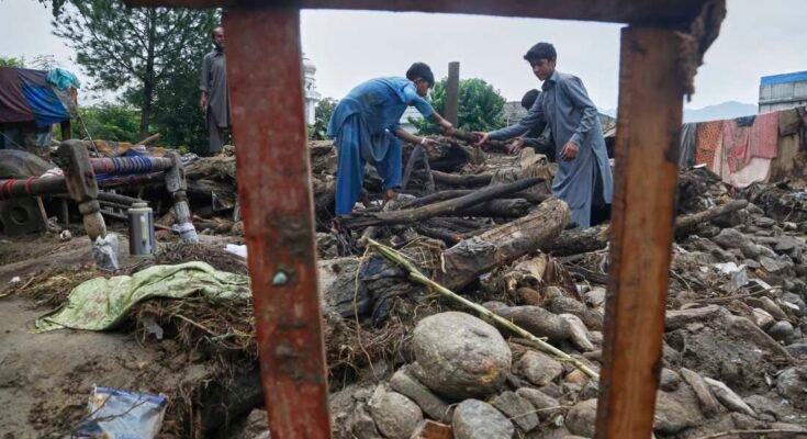 Los niños recolectan madera y otros objetos útiles a través de los escombros de su casa dañada después de las inundaciones repentinas el viernes en un distrito de Pir Baba, un área del distrito de Biner, en el noroeste de Pakistán el 17 de agosto de 2025.