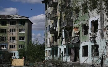 Los residentes usan hojas de madera contrachapada para cubrir las ventanas rotas en un edificio residencial que está fuertemente dañado después de una huelga rusa en la ciudad de Bilozerske, en la región de Donetsk, el 12 de agosto, en medio de la invasión rusa de Ucrania.
