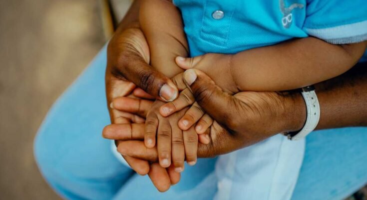 Mano de la madre africana y cerrada de la mano del niño africano