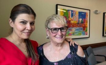Rachel Nassif tiene su brazo alrededor del hombro Roberta Rabinovitz. Las dos mujeres se paran frente a una pintura colorida y sonriente.